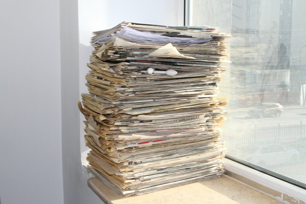 a stack of newspapers sitting on top of a window sill